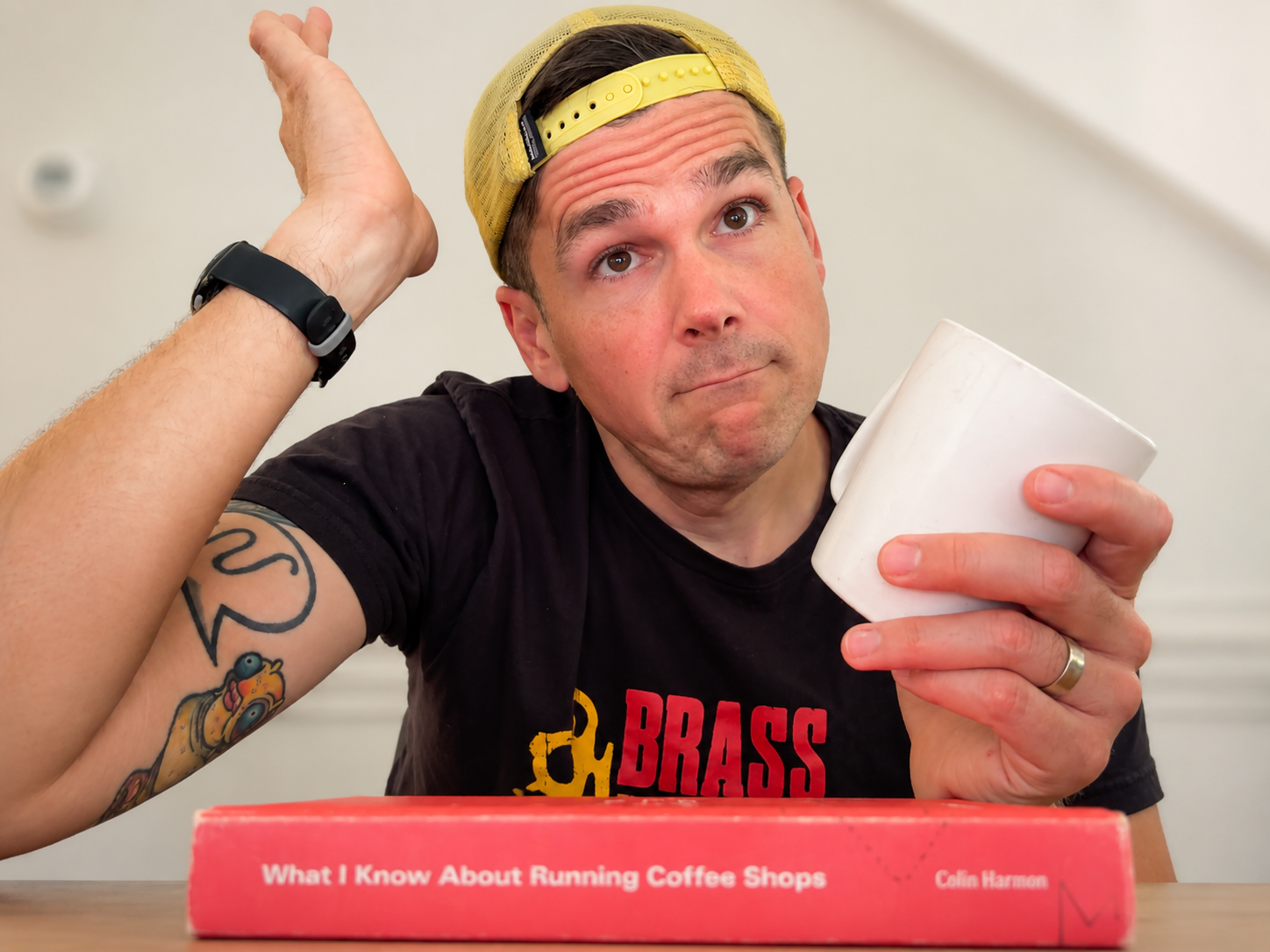 Dave holding a coffee cup with a coffee shop book in front of him